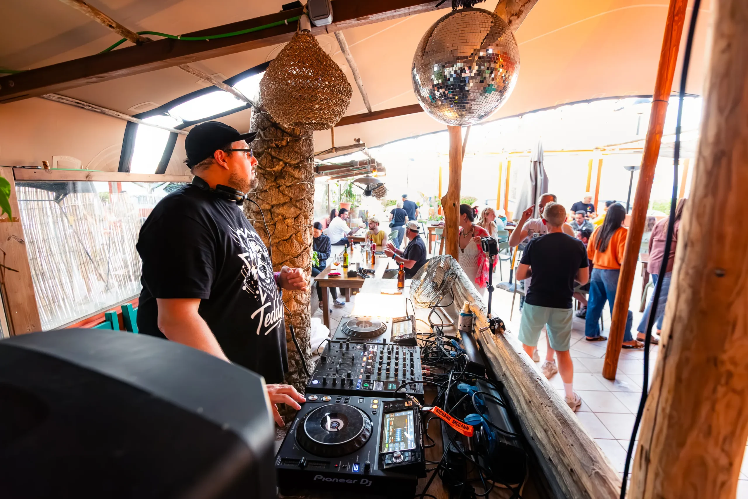 DJ Teddy D performing in front of a lively crowd with warm concert lighting