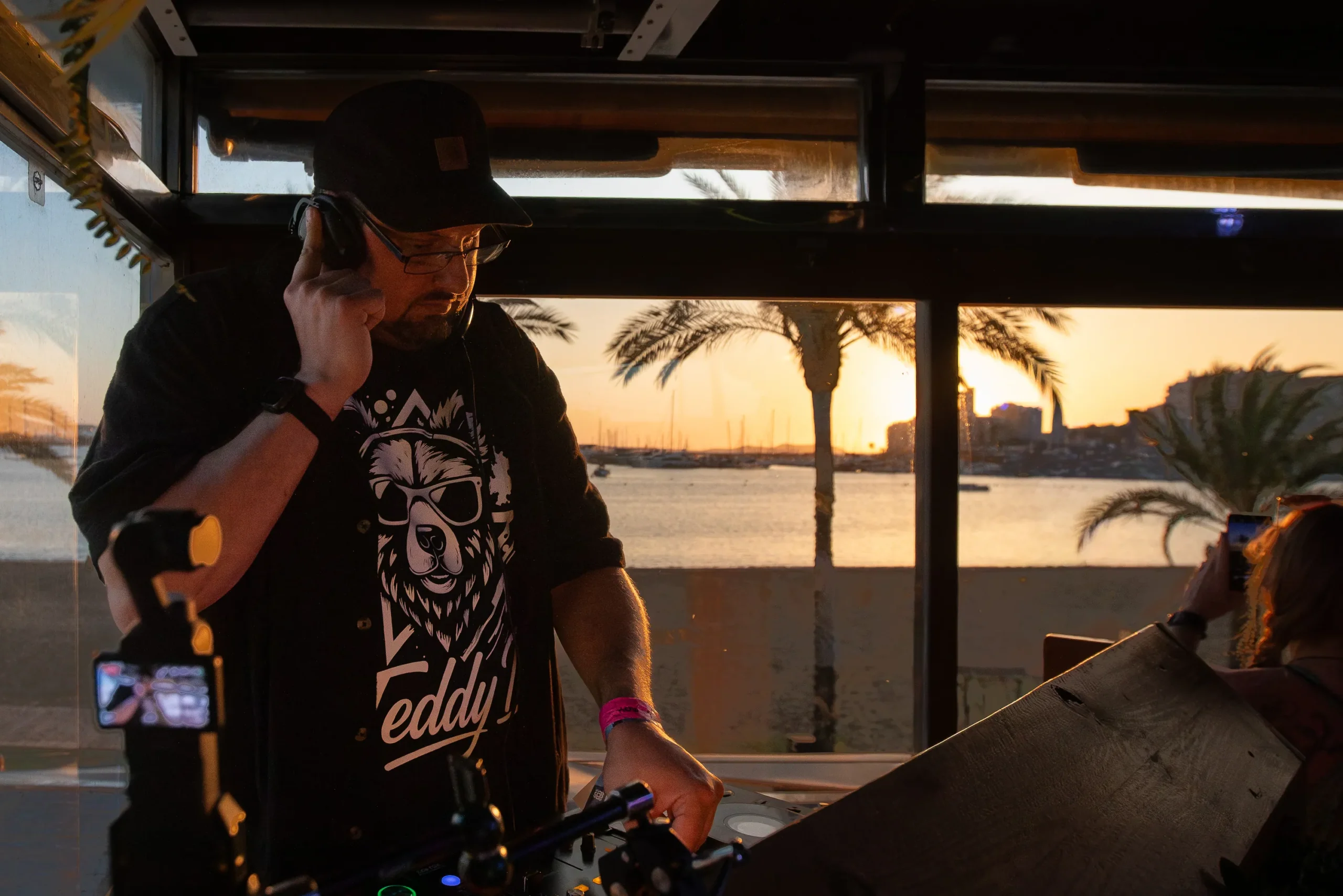 DJ Teddy D performing live with vibrant stage lighting and an energetic crowd atmosphere